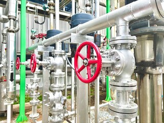 pipes and valves, Close-up of industrial pipeline system with red-handled valve and pressure gauge. Used in HVAC, water distribution, and process control systems.