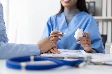 Doctor is explaining taking medicine to a patient in the examination room. Health consultant from a...