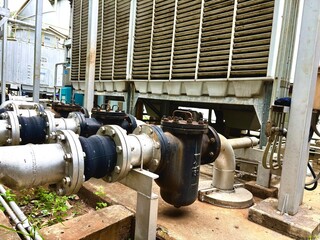 Industrial cooling tower with connected insulated pipelines and filters. Essential part of HVAC and thermal systems used in large buildings or factories.