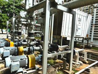 old industrial machine, Industrial cooling tower system emitting vapor under blue sky. Heavy-duty piping, valves, and heat exchangers in a manufacturing or refinery plant exterior.