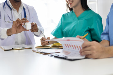 Medical team discussing treatment plan during meeting, analyzing data and prescriptions in...