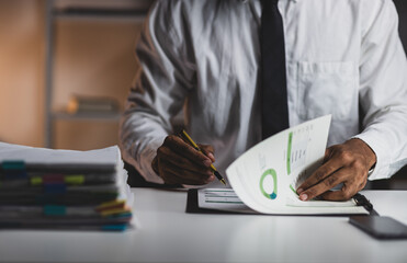 Businessman analyzing financial charts and reports working late. Businessman working late,...
