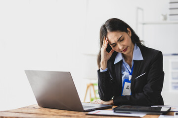 Stressed Asian businesswoman with headache from overwork on laptop in office, burnout and anxiety...