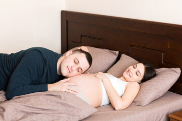 Pregnant woman with her husband in bed in the morning