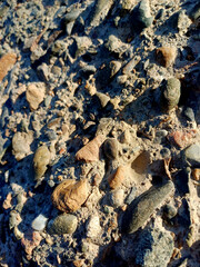 Detailed view of textured gravel surface with various stone shapes and colors in natural light during the afternoon