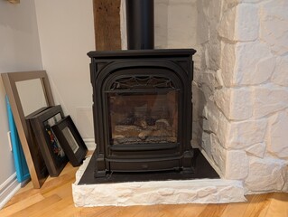 Cozy indoor scene with a black cast iron fireplace and stacked picture frames, set against a rustic...