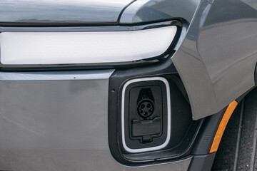 Close-up of the charging port in an electric vehicle near the headlight. The details of the port...