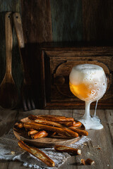 Glass of beer and salted crackers on a wooden rustic table