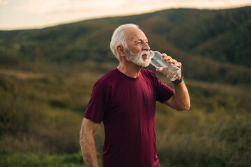 Elderly Man Drinking Water in Scenic Nature Setting