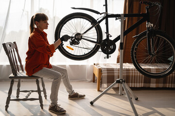 Woman tightening bolts with wrench fixing bicycle wheel repairing bike DIY at home