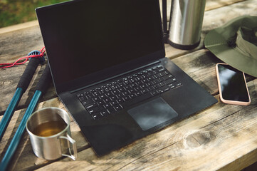 Outdoor Workspace Featuring a Laptop, Mobile Phone, and Accessories on a Wooden Table