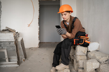 Female Builder using smartphone during work break in old building