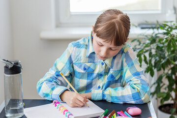 Focused young girl drawing at home desk