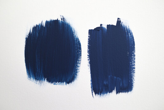 Blue paint samples white wall. Test paint patches side-by-side for painting a blue. accent wall. 2 blue brush stroke swatches for choosing paint color. DIY interior decoration. Selective focus.