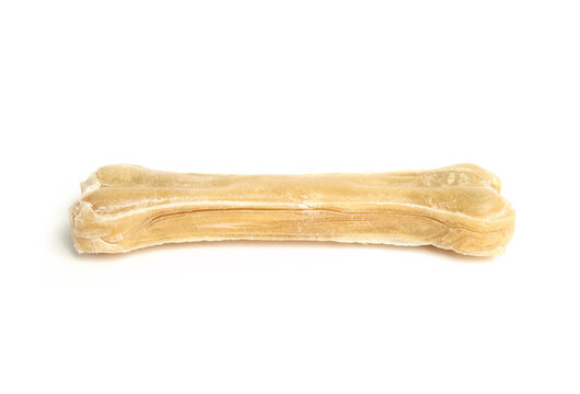 Isolated rawhide chew bone for dogs. Side view of dental health chew stick in bone shape. Used for dogs and puppy enrichment, dental health and happiness. Selective focus. White background.