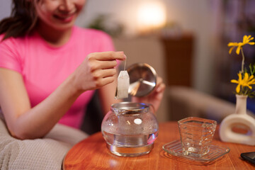 Asian Adult Woman Brewing Tea with Teabag for Wellness Lifestyle Enjoying Hot Beverage and Herbal Infusion in Cozy Setting for Relaxation at Home