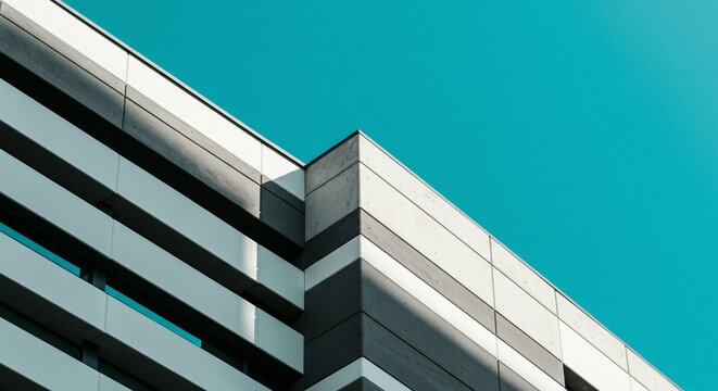 Low angle view of modern building exterior with clean lines and vibrant blue sky overhead.