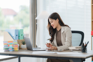 Focused Professional in Modern Office: A stylish businesswoman, illuminated by natural light,...