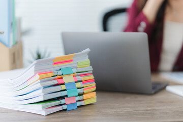 Stack of documents and a woman: A close-up shot of a stack of documents, neatly organized with...
