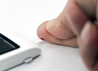 Person using blood glucose test device to check their blood sugar level by pricking their finger....