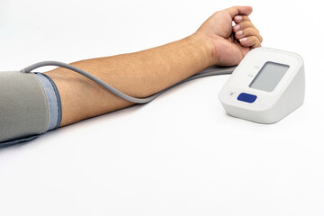 Person is using digital blood pressure monitor on their arm, displaying health checkup process. device is placed on white surface, emphasizing its modern design