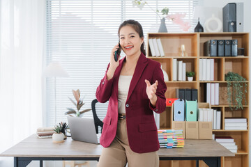 Businesswoman in the Office: A radiant businesswoman, stands confidently while talking on her...