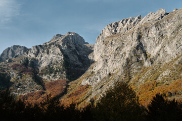 Sharp ridges and colorful forested slopes of the Prokletije mountains in autumn, captured in warm...
