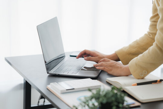 Focused Work: A person diligently working at a sleek, modern workstation. Hands poised over a laptop keyboard, showcasing productivity and focus, bathed in natural light.