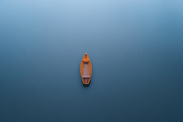 Peaceful Wooden Boat Floating on a Calm Lake at Sunset, Reflecting Serene Hues of Blue and Gold