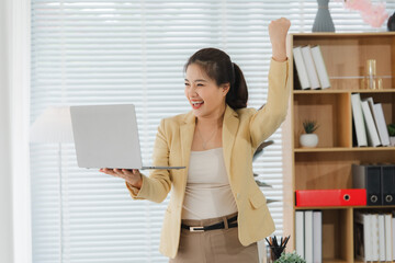 Businesswoman Celebrates Success with Laptop: A joyful woman beams with delight, celebrating her...