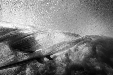 Surfer lit by dramatic shadows and highlights in the wave