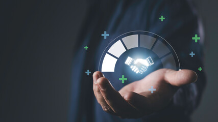 Hand holding glowing handshake icon with progress graphic, representing trusted partner, business relationship, collaboration, reliability, and long-term success.