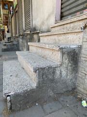 Steps, stairs, old concrete steps in front of closed entrance, staircase features rough stone texture and visible wear, creating urban street atmosphere
