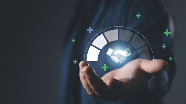 Hand holding glowing handshake icon with progress graphic, representing trusted partner, business relationship, collaboration, reliability, and long-term success. - Powered by Adobe