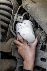 Mechanic's hand reaches out to install or remove an oil filter on the underbody of a car. Changing an oil filter