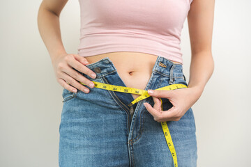 Fat belly, chubby asian young woman use tape measuring around waist tight jeans, obese girl excess...