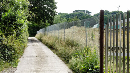 concrete road by a wire fence with a gate