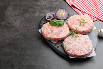 Fresh raw patties for burger and spices on grey table, closeup. Space for text