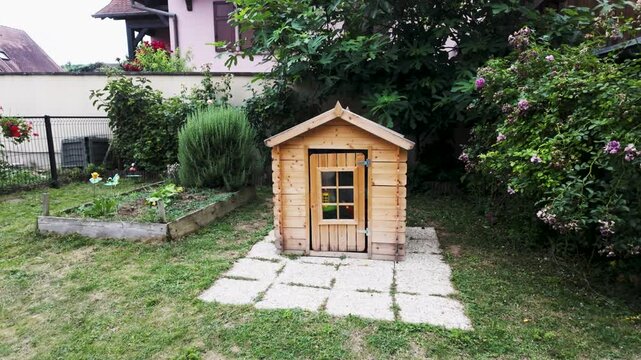 Maisonnette pour enfant en bois dans un jardin, toit fen&ecirc;tre et porte vitr&eacute;e 
