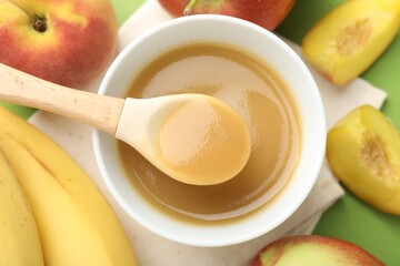 Baby food. Tasty puree in bowl and ingredients on green background, flat lay
