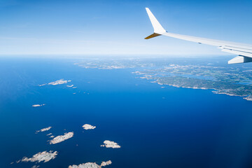 Airplane wing seen from window. Airplane flight over sea and land.