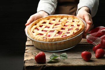 Woman with tasty strawberry pie at wooden table, closeup