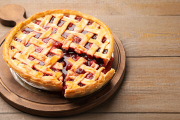 Tasty cut cherry pie on wooden table, closeup. Space for text