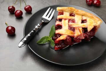 Piece of tasty cherry pie and berries on grey table, closeup