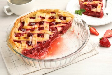 Tasty cut strawberry pie and berries on white wooden table, closeup