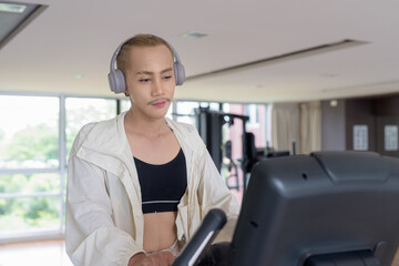 Non-binary gay man with mustache and androgynous appearance working out indoors in gym. Wearing...