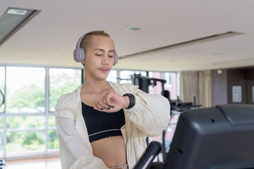 Non-binary gay man with mustache and androgynous appearance working out indoors in gym. Wearing...