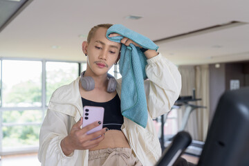 Non-binary gay man with mustache and androgynous appearance working out indoors in gym. Wearing...
