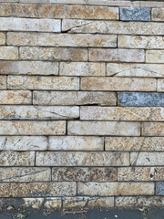 Wall of brick, fragment of old stone wall made of rectangular beige blocks with visible texture, stains, and natural cracks, weathered surface with earthy tones and rustic appearance