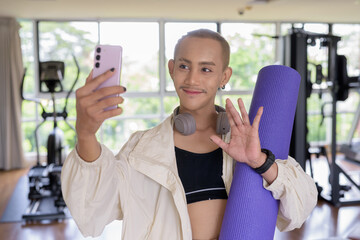 Non-binary gay man with mustache and androgynous appearance working out indoors in gym. Wearing...
